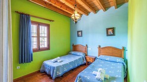A room with two wooden beds, a window with curtains, and a wooden ceiling.