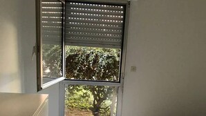 A bedroom with a bed, a window with a view of trees, and a sliding door. - Nice apartment Uzès center (Uzès)