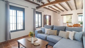 Uma sala de estar com um sofá, uma mesa de centro e um vaso com flores.