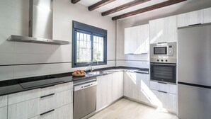 Uma cozinha moderna com armários brancos, fogão de aço inoxidável, forno embutido e lava-louças.