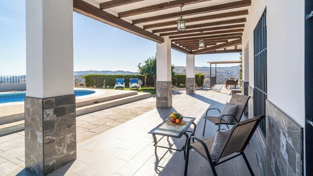 Um alpendre coberto com piscina, área de estar externa e vista para montanhas.