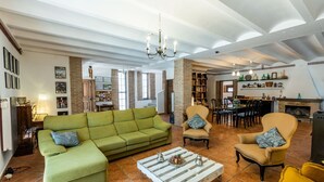 A spacious living room with a green sofa, two armchairs, and a coffee table. There is a fireplace, a dining area, and a kitchen visible in the background. - Caserío Lo Bulle Oria by Ruralidays (Almería)