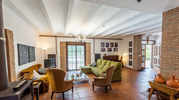 A spacious living room with a green sofa, two armchairs, a coffee table, and a fireplace. - Caserío Lo Bulle Oria by Ruralidays (Almería)