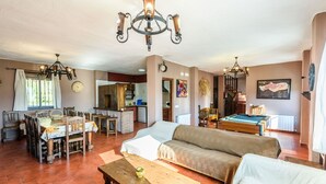 A cozy living room with a sofa, dining table, and a pool table. There is a kitchen area in the background. - La Mina Benaoján by Ruralidays (Málaga)