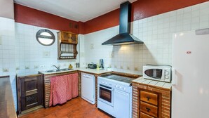 A compact kitchen with a stove, oven, microwave, and a sink. - La Mina Benaoján by Ruralidays (Málaga)