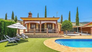 Une villa avec piscine, espace salon extérieur et jardin.