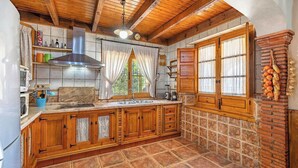 Une cuisine avec des meubles de rangement en bois, une hotte de cuisinière en acier inoxydable, un évier et une fenêtre avec des rideaux.