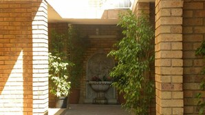 A brick corridor with potted plants and a stone fountain. - Croydon hotel (Kempton Park)