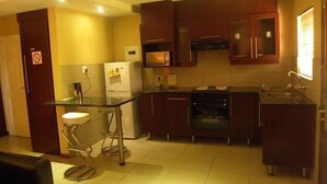A compact kitchen with a refrigerator, microwave, stove, and sink. - Croydon hotel (Kempton Park)