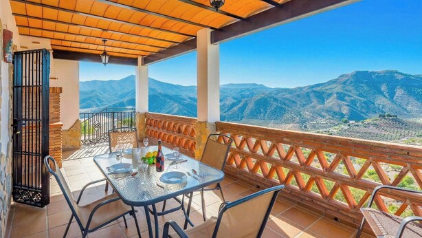 A terrace with a table set for dining, a view of mountains, and a wooden ceiling. - El Algarrobo de Alora Álora by Ruralidays (Málaga)