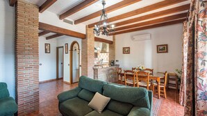 A living room with a green sofa, wooden dining table, and a brick fireplace. - El Algarrobo de Alora Álora by Ruralidays (Málaga)