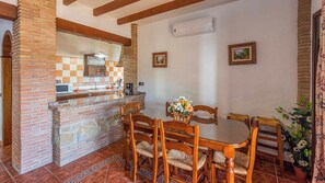 A kitchen with a brick wall, a dining table with chairs, and a hanging light fixture. - El Algarrobo de Alora Álora by Ruralidays (Málaga)
