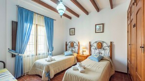 A room with two beds, wooden headboards, a ceiling fan, and a wooden wardrobe. - El Algarrobo de Alora Álora by Ruralidays (Málaga)