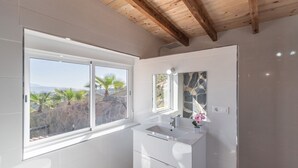 Un baño con un ventanal grande, un lavamanos y un espejo.