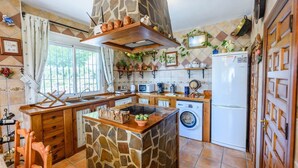 Una cocina con una isla de piedra, armarios de madera, lavadora y refrigerador.