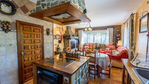 Una cocina acogedora con una isla de madera, detalles de piedra y una zona de comedor con un sofá rojo.