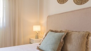 Cama bem arrumada com duas almofadas, um abajur e uma parede decorada com duas peças de arte circulares.