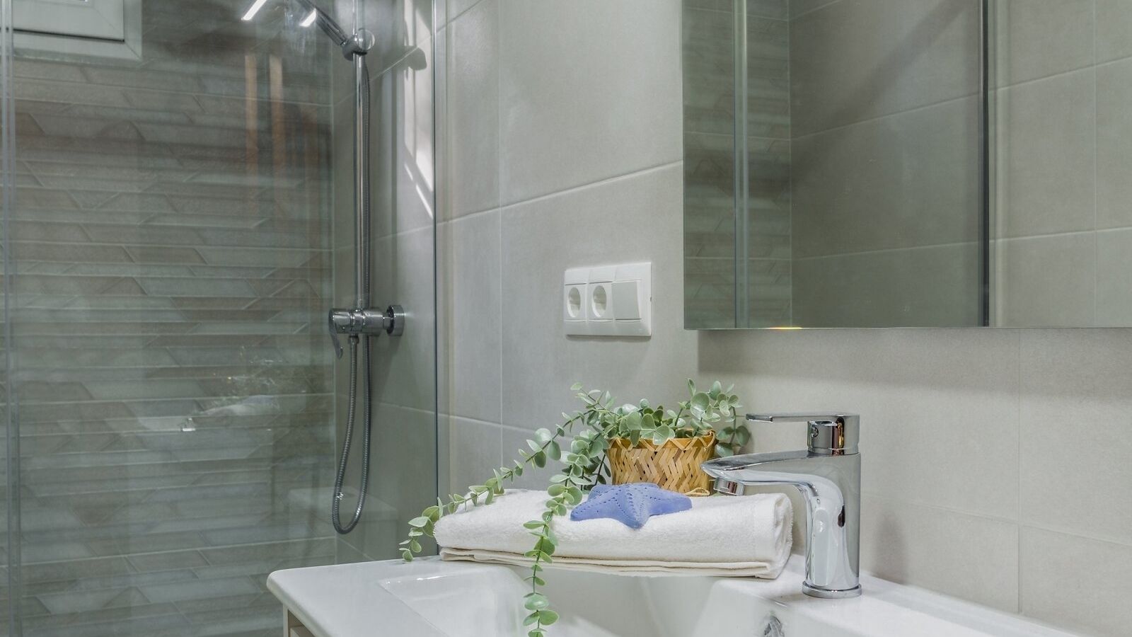 Une salle de bain avec une douche à parois de verre, un lavabo blanc et un miroir au-dessus du lavabo.