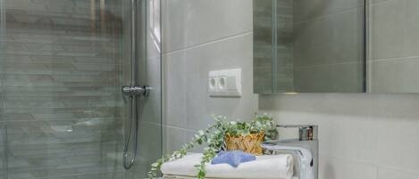 Une salle de bain avec une douche à parois de verre, un lavabo blanc et un miroir au-dessus du lavabo.