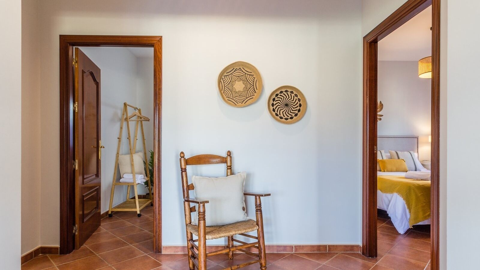 A room with a wooden chair, a ladder, and two wall decorations.