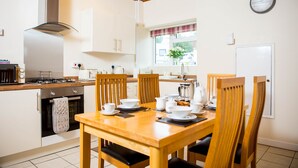 Una cocina moderna con armarios de madera, una estufa a gas y una mesa de comedor lista para cuatro comensales.