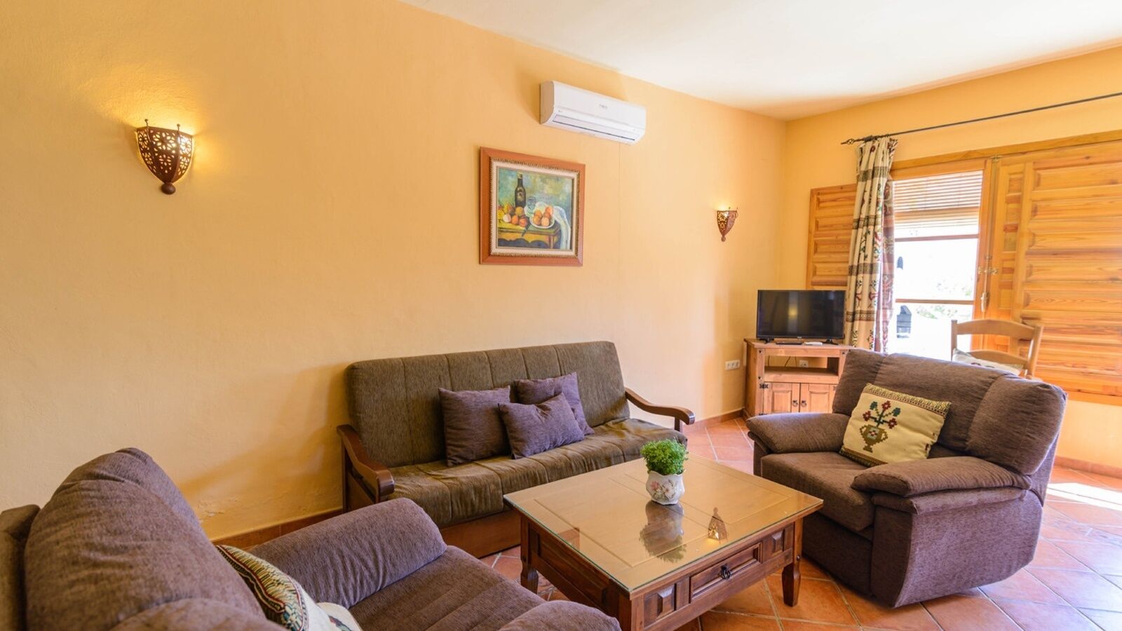 Ein gemütliches Wohnzimmer mit einer Couch, zwei Sesseln, einem Couchtisch und einem Fernseher.