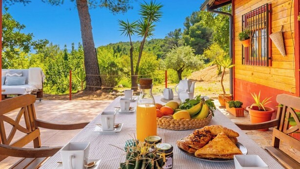 A table set for breakfast with a view of a forested landscape. - Hornillos Alozaina by Ruralidays (Málaga)