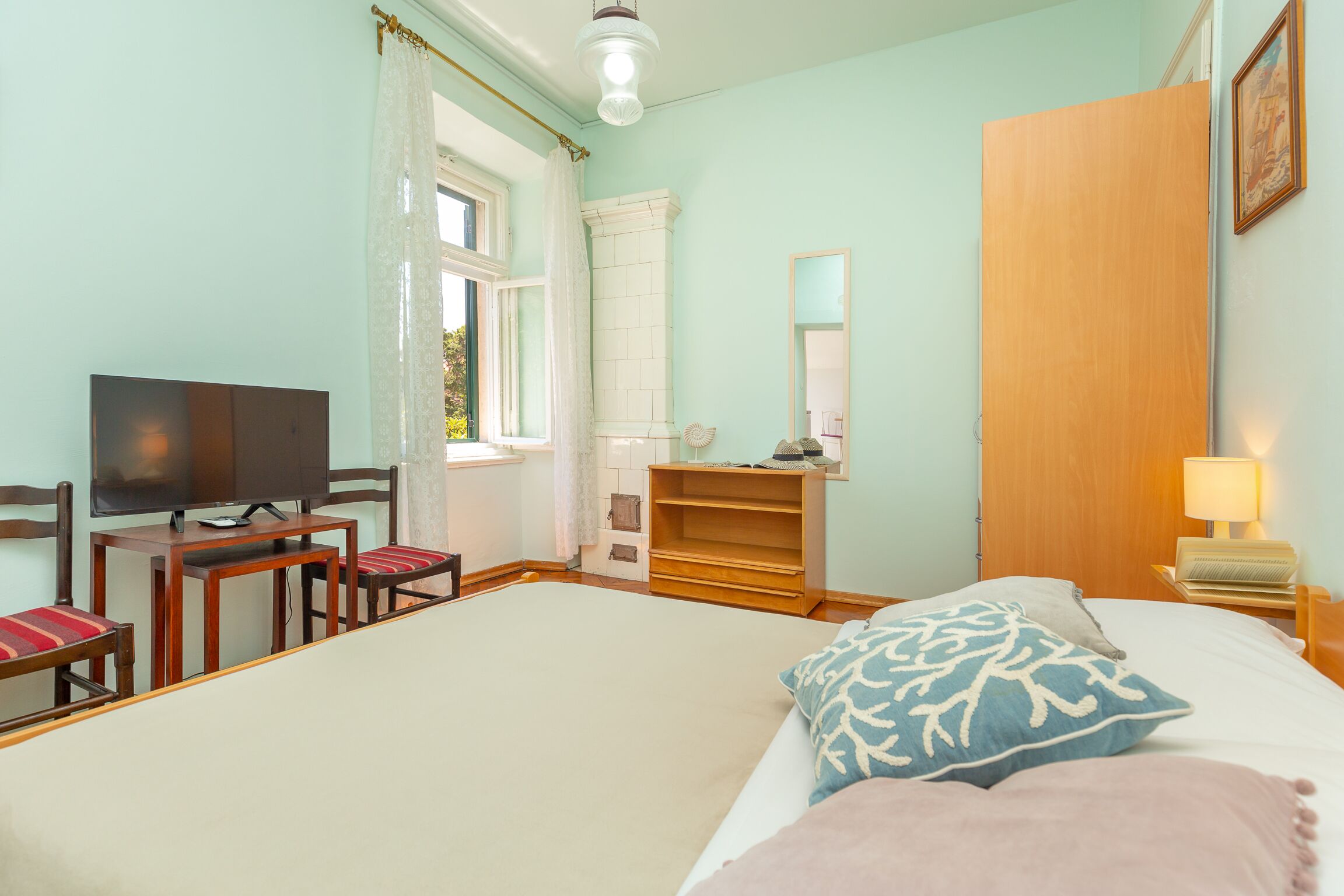Un dormitorio con cama, televisión, escritorio con sillas, armario y espejo.