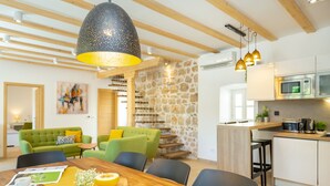 A modern kitchen with a wooden table, chairs, and a large hanging light fixture. - Hedera Estate, Villa Hedera IV (Dubrovnik)