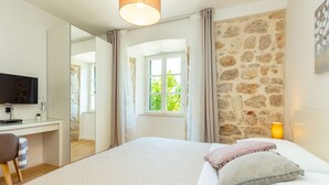 A bedroom with a bed, a desk, a television, and a window with curtains. - Hedera Estate, Villa Hedera IV (Dubrovnik)