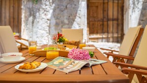 A wooden table set with breakfast items, including croissants, orange juice, and a newspaper. - Hedera Estate, Villa Hedera IV (Dubrovnik)