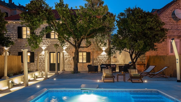 A swimming pool with lounge chairs and a stone building in the background. - Hedera Estate, Villa Hedera IV (Dubrovnik)