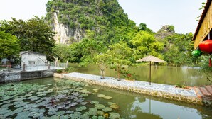 A serene pond with lily pads, a small bridge, and a mountain backdrop. - Ninh Binh Valle Montana homestay (Hoa Lu)
