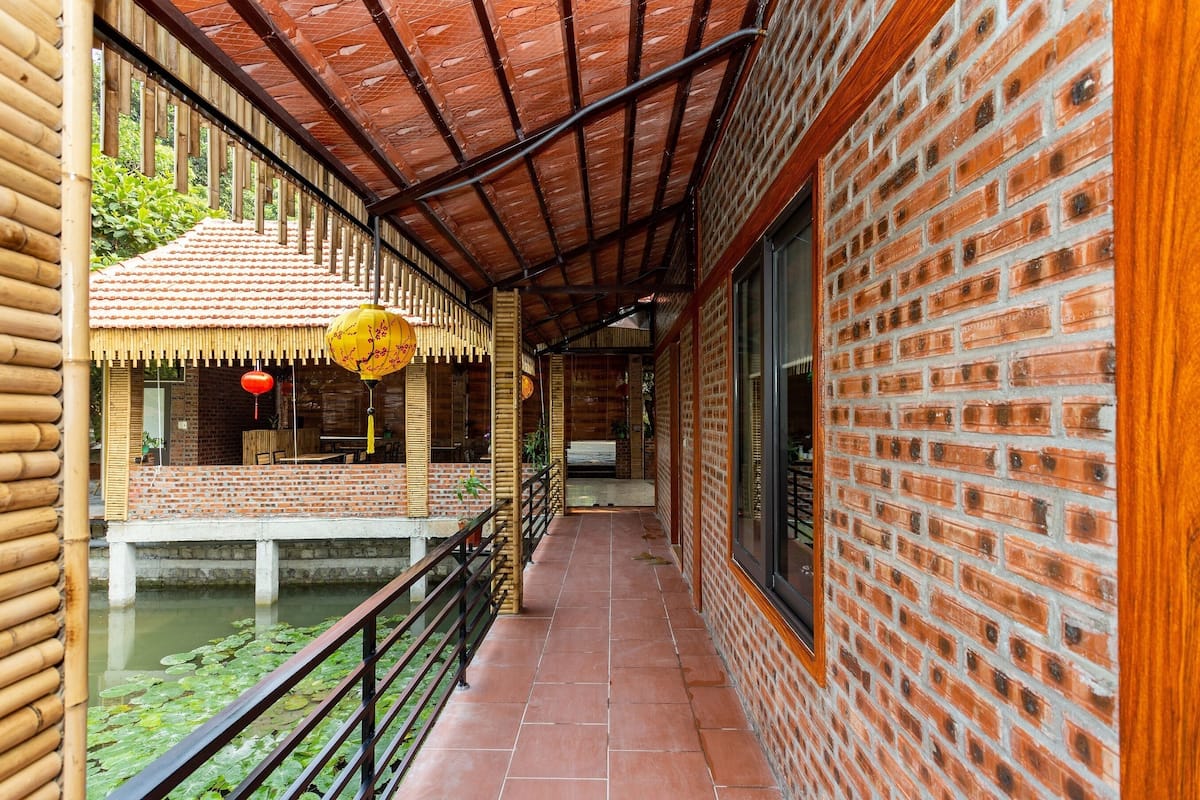 A corridor with a tiled floor, brick walls, and a wooden railing.