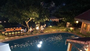 A swimming pool surrounded by outdoor seating and string lights. - Ninh Binh Valle Montana homestay (Hoa Lu)