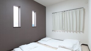 Une chambre avec deux lits, une fenêtre et un rideau.