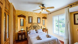 A bedroom with a bed, a ceiling fan, a window with curtains, and framed pictures on the wall. - Villa Jiminez - A104 Coín by Ruralidays (Málaga)