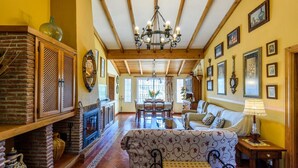 A spacious living room with a fireplace, a chandelier, and a dining area with a table and chairs. - Villa Jiminez - A104 Coín by Ruralidays (Málaga)