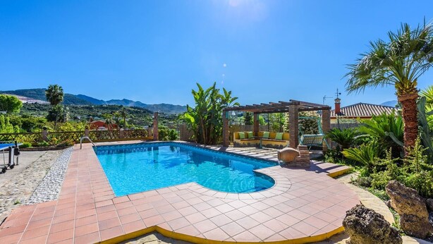 A swimming pool with a tiled deck, surrounded by plants and a pergola. - Villa Jiminez - A104 Coín by Ruralidays (Málaga)