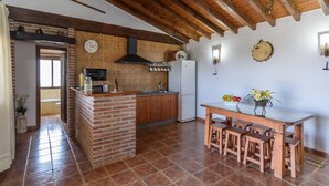 Une cuisine avec un îlot central en briques, des meubles en bois, un four à micro-ondes et un réfrigérateur.