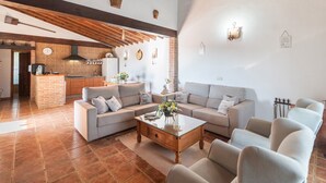 Un vaste espace de vie comprenant un grand canapé, une table basse en bois et une cuisine à l’arrière-plan.