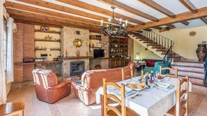 A cozy living room with leather sofas, a dining table set, a fireplace, and a staircase leading to another level.