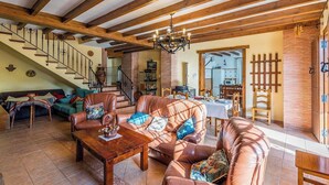 A spacious living area with leather sofas, a wooden coffee table, and a staircase with exposed beams.