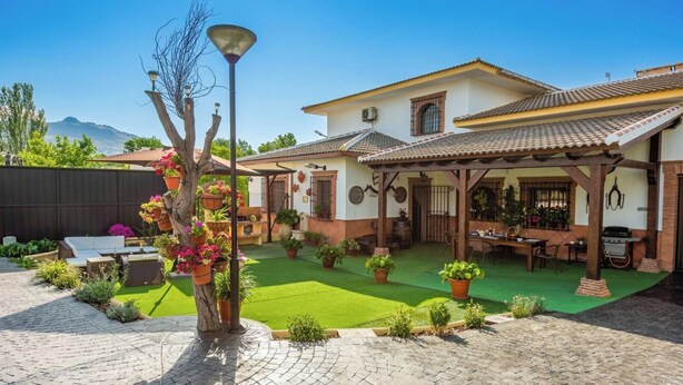 A house with a patio, outdoor seating, a barbecue area, and a small garden.