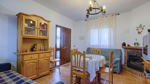 Ein gemütliches Wohnzimmer mit Esstisch, Stühlen, einer Couch, einem Holzschrank und einem Kamin.
