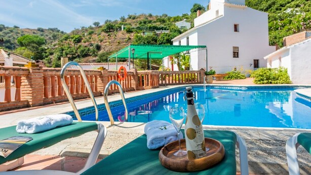 A poolside area with lounge chairs, a bottle of champagne, and a towel. - Molino del Alferez Sayalonga by Ruralidays (Málaga)