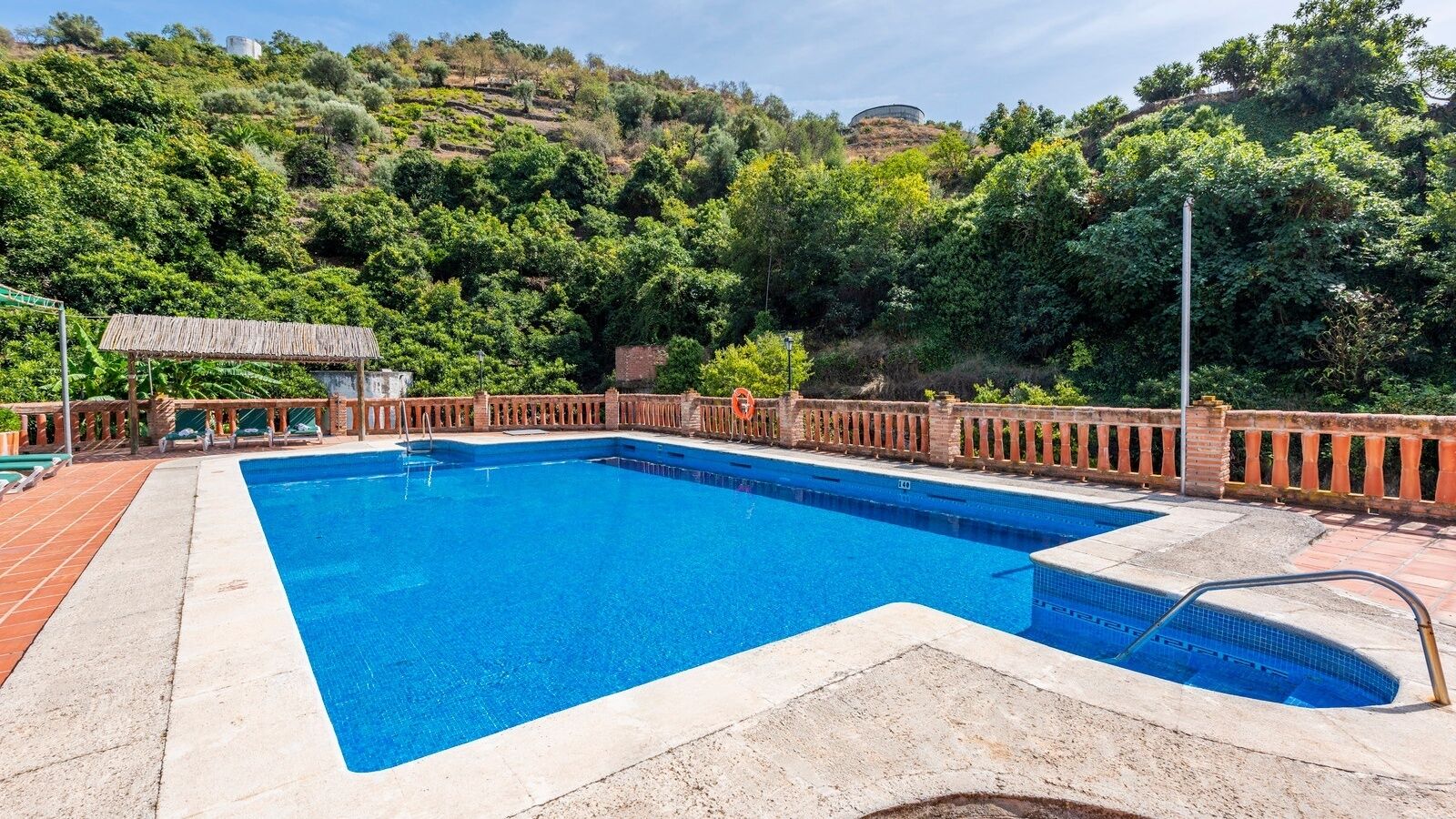 A rectangular swimming pool with a tiled deck area and a lifeguard stand.