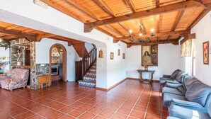A spacious living area with a wooden ceiling, a staircase, a dining area, and a sofa. - Molino del Alferez Sayalonga by Ruralidays (Málaga)