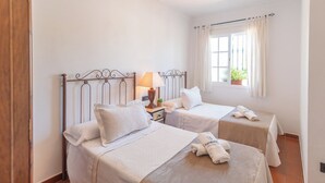 Une chambre d’hôtel avec deux lits, une table de chevet avec une lampe et une fenêtre avec des rideaux.