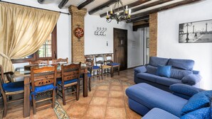 Un coin repas avec des chaises et une table en bois, un canapé bleu et un lustre.